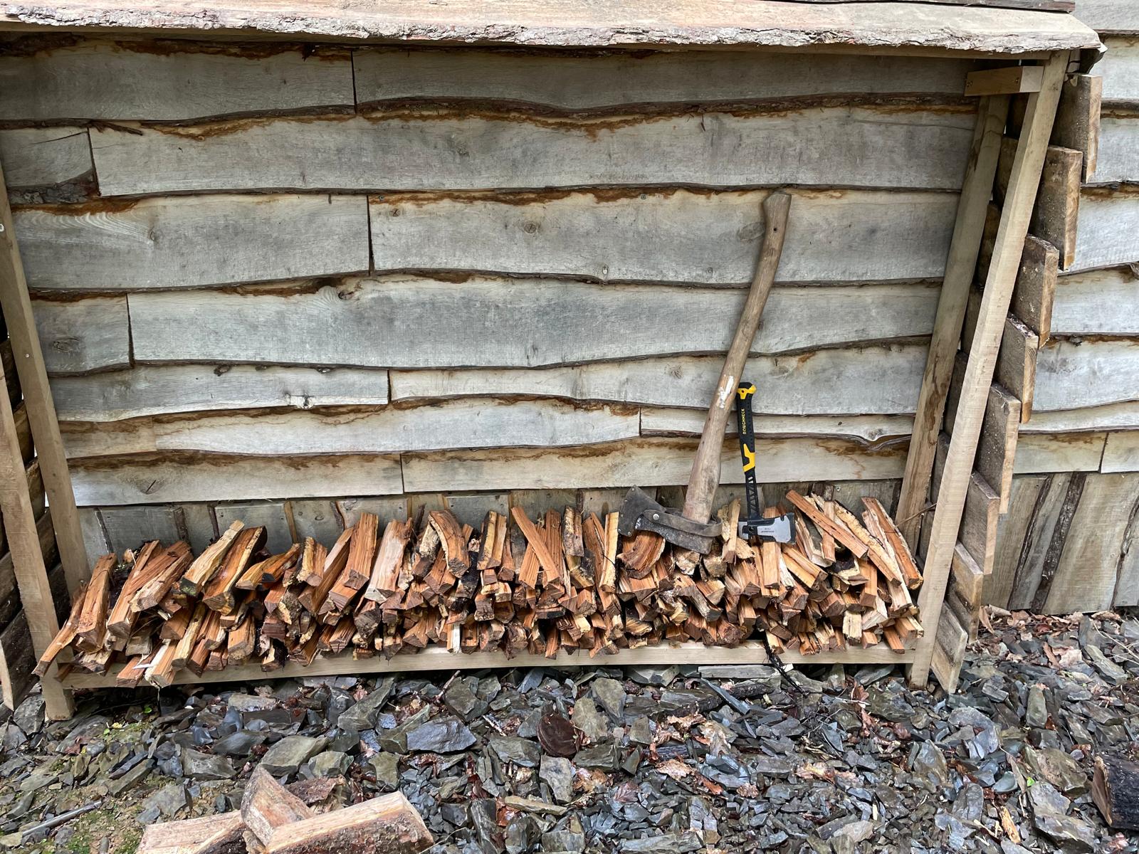 Cabin exterior with timber log shelter and fresh firewood piles in Carmarthenshire